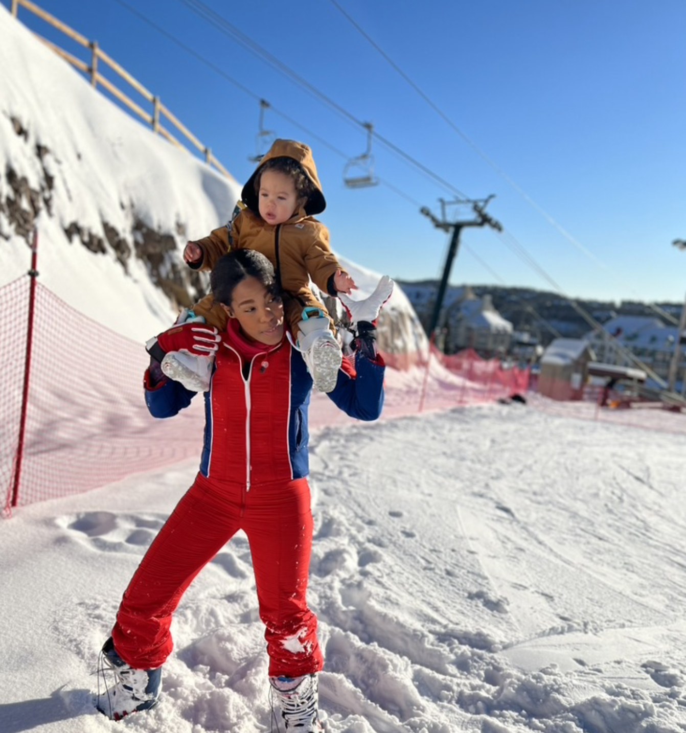Sojourn Wallace carrying her son on her shoulders on the ski slope